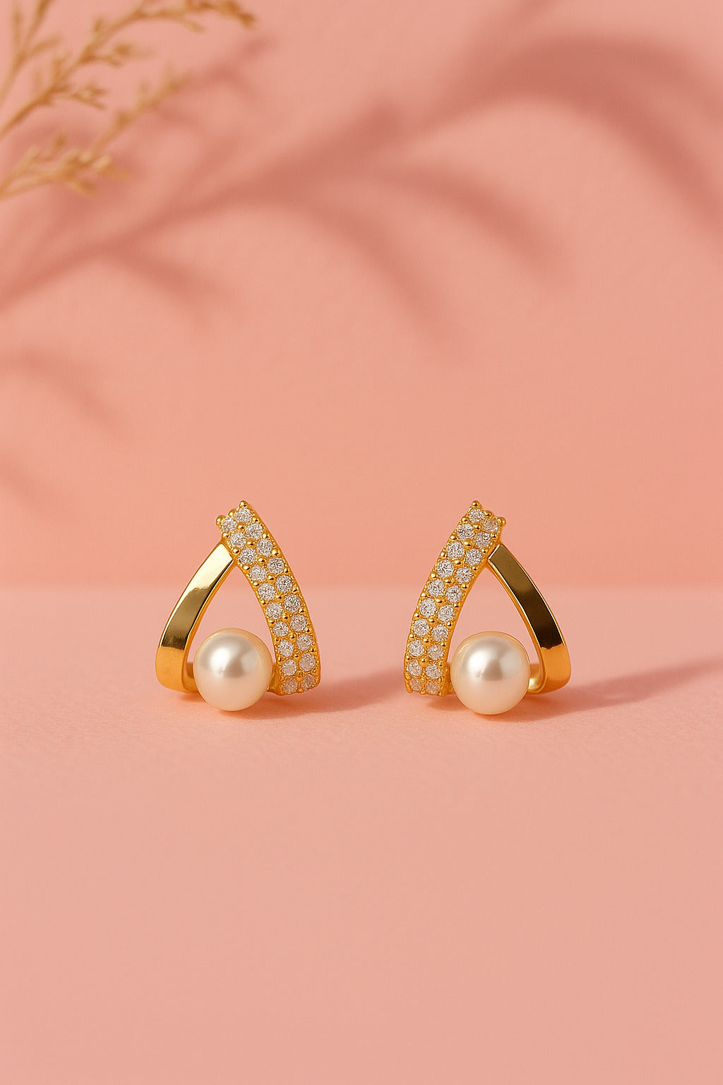 Gold earrings with pearls on a pink background