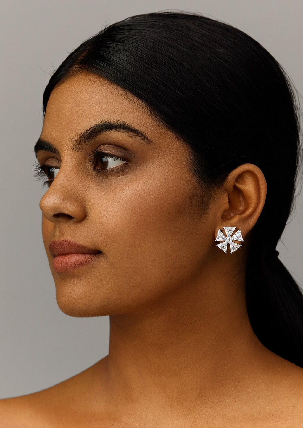 Woman wearing a silver earring against a neutral background
