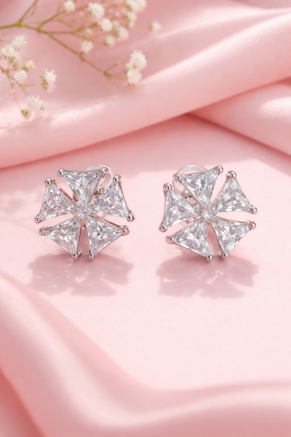 Pair of diamond stud earrings on a pink fabric background