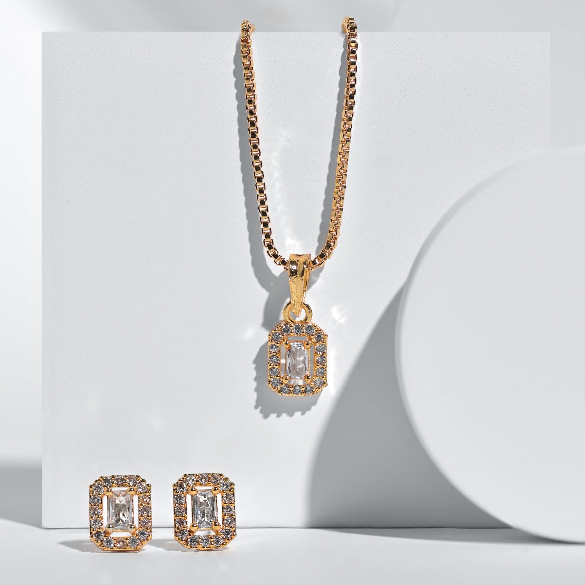 Gold necklace and earrings set on a white background