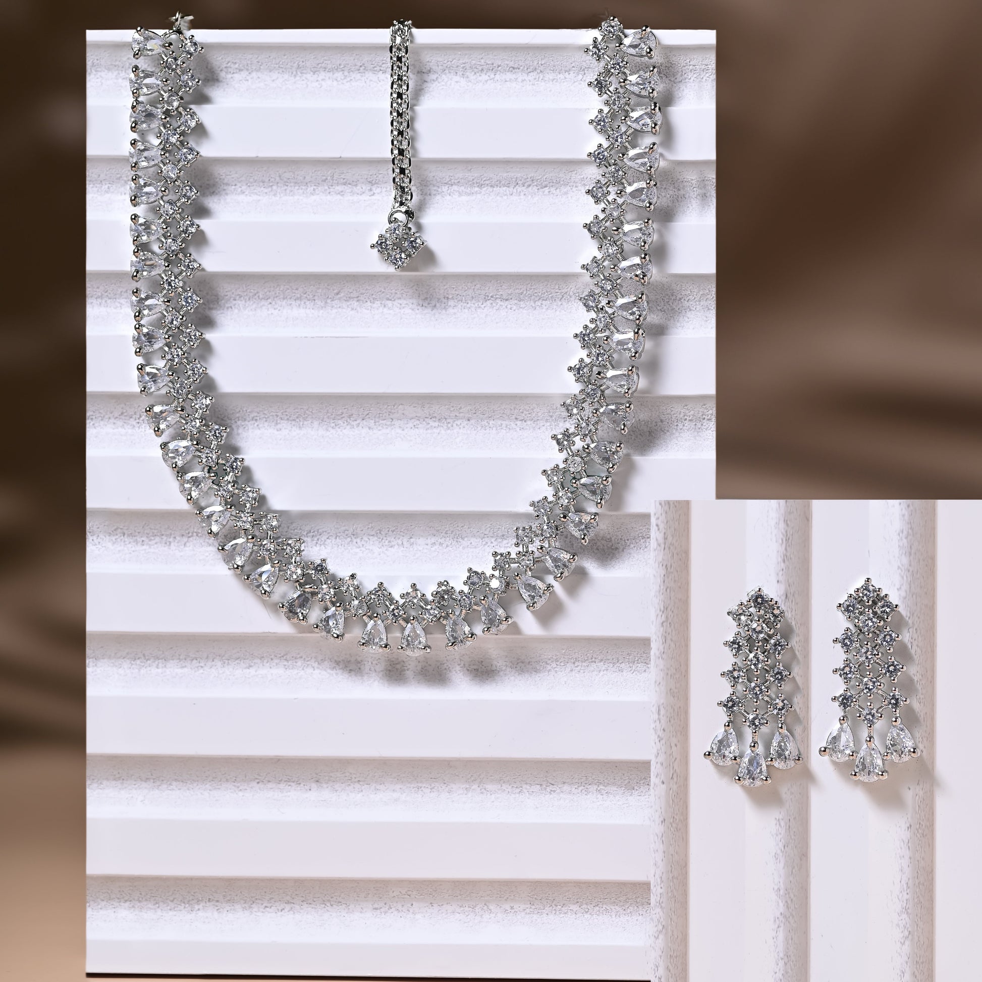 Silver necklace and earrings on a white striped background
