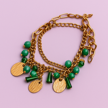 Gold bracelet with green beads on a pink background
