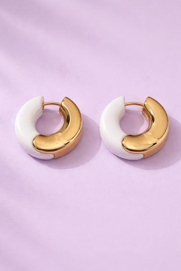 Pair of gold and white hoop earrings on a light purple background