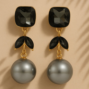 Pair of earrings with black gemstones and gray pearls on a beige background