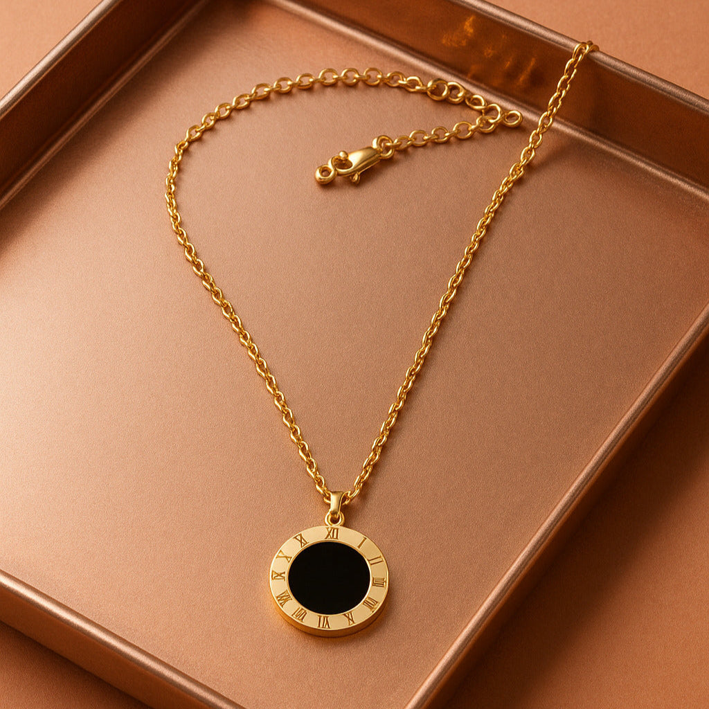 Gold necklace with a black pendant on a brown surface