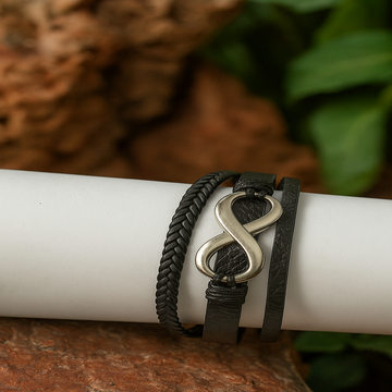 Black braided leather bracelet with a silver infinity symbol on a white surface.