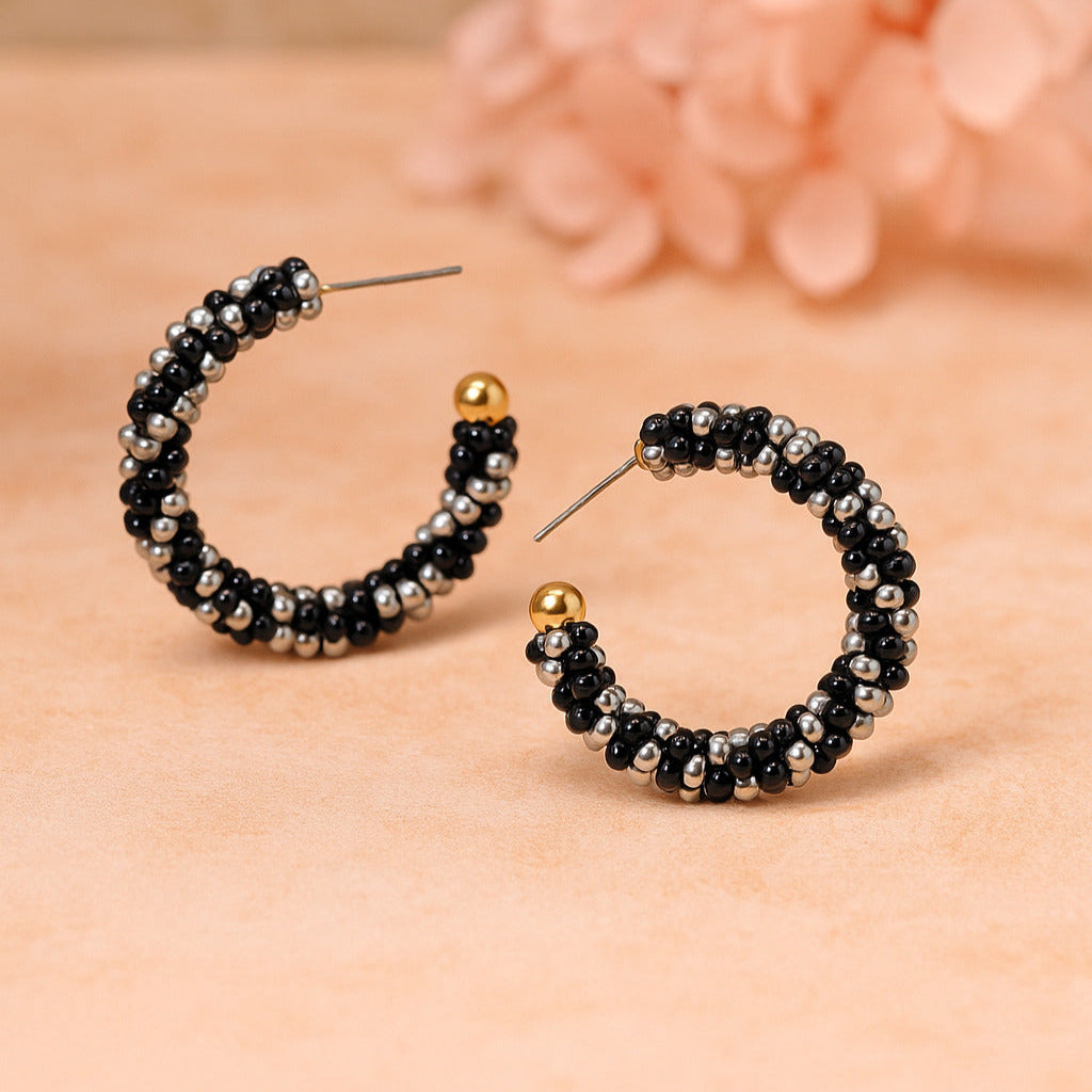 Beaded hoop earrings on a beige surface with a blurred floral background