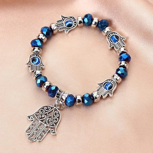Bracelet with blue beads and silver Hamsa hand charms on a beige background