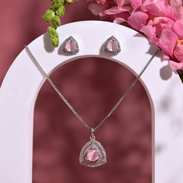 Jewelry set with pink heart-shaped gemstones on a white arch with flowers in the background