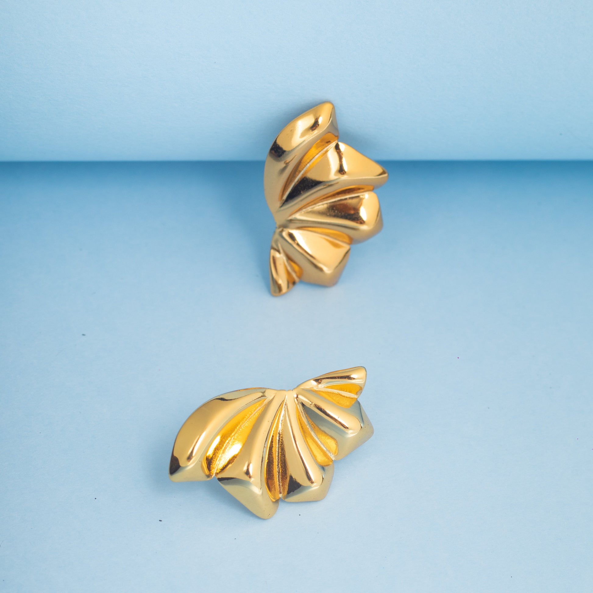 Pair of gold earrings on a light blue background