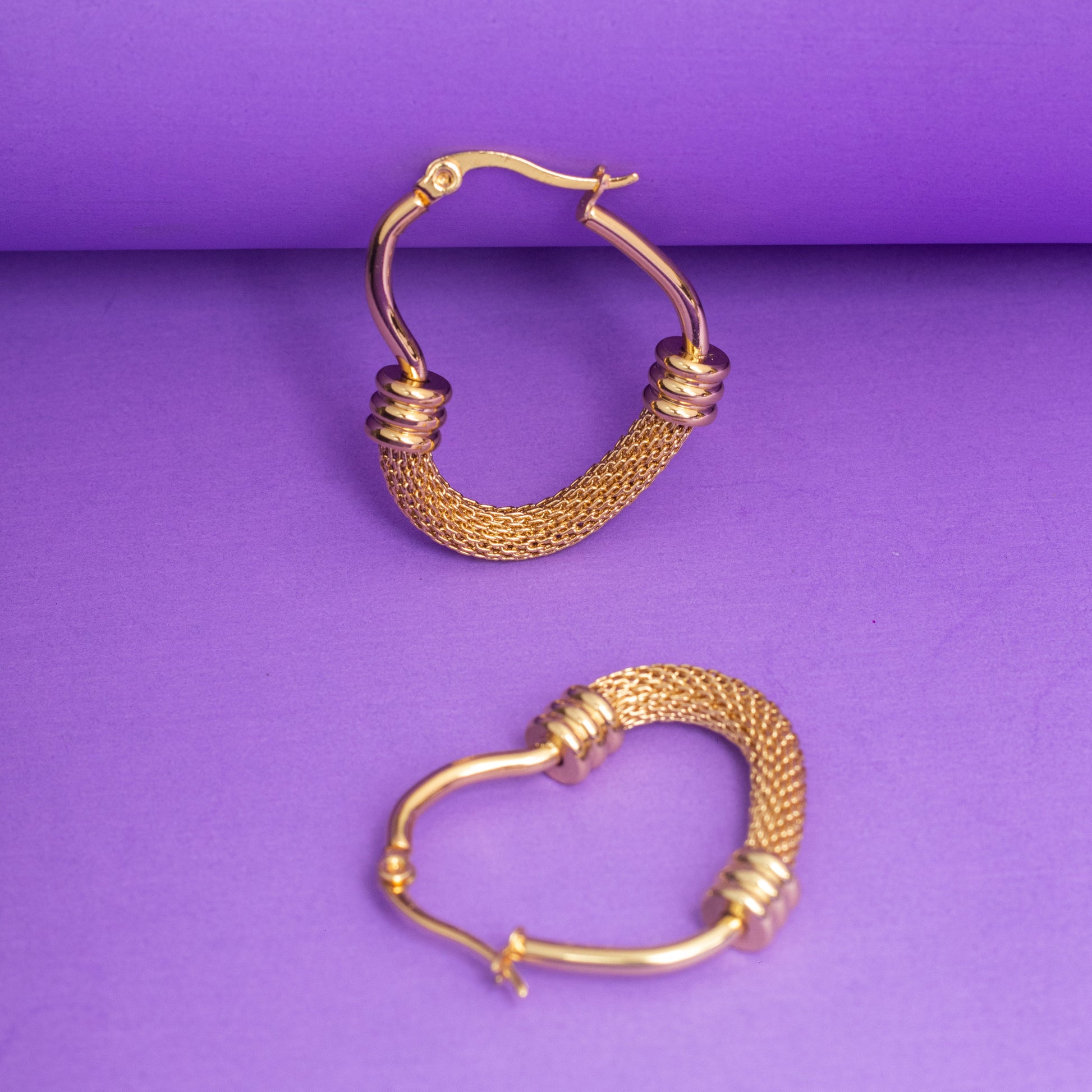 Gold hoop earrings on a purple background