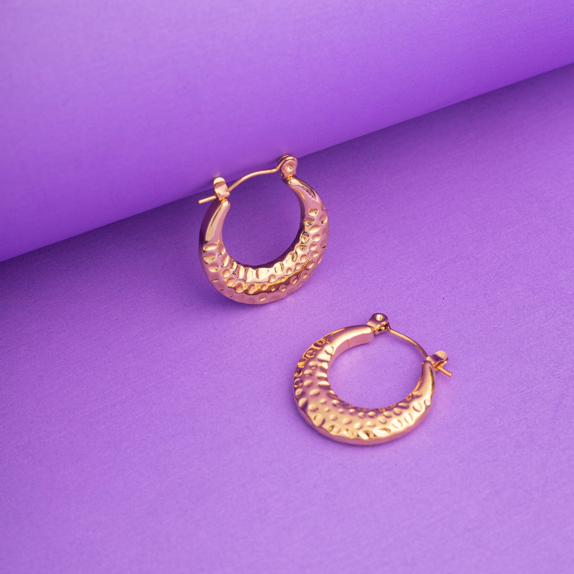 Gold hoop earrings on a purple background
