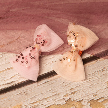 Two decorative bows with sequins on a textured surface