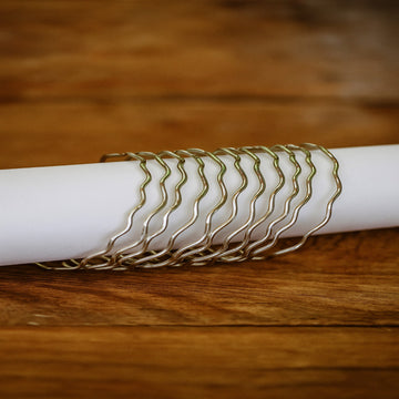 Gold bracelet on a white roll of paper against a wooden background