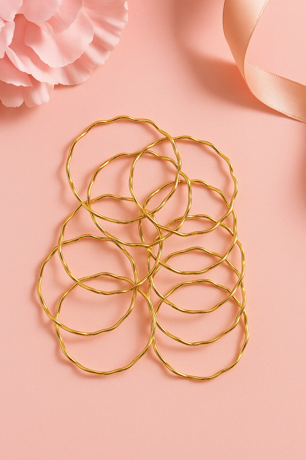 Set of gold hair ties on a pink background with flowers and ribbons.
