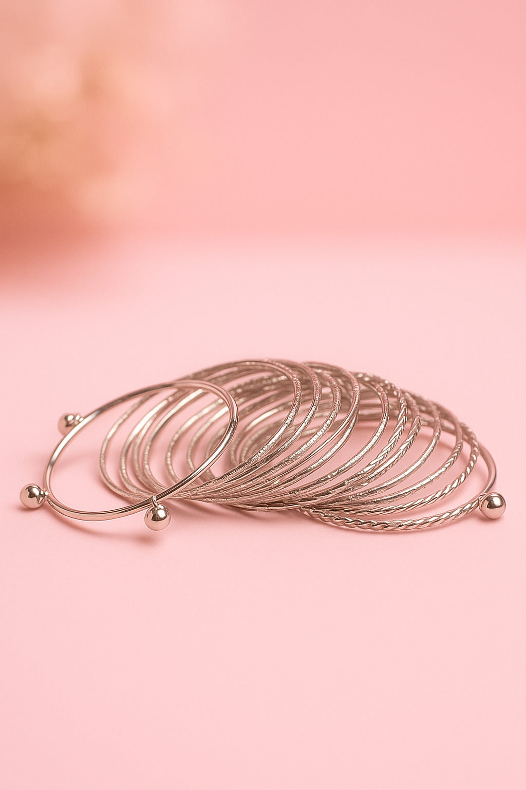 Set of silver bangles on a pink background