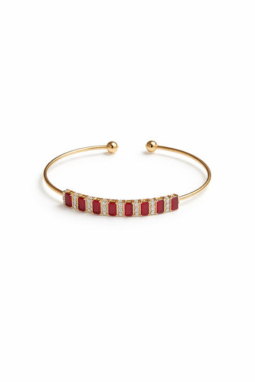 Gold bracelet with red stones on a white background