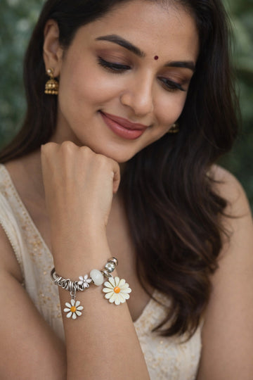 Woman wearing a bracelet with floral designs against a blurred natural background
