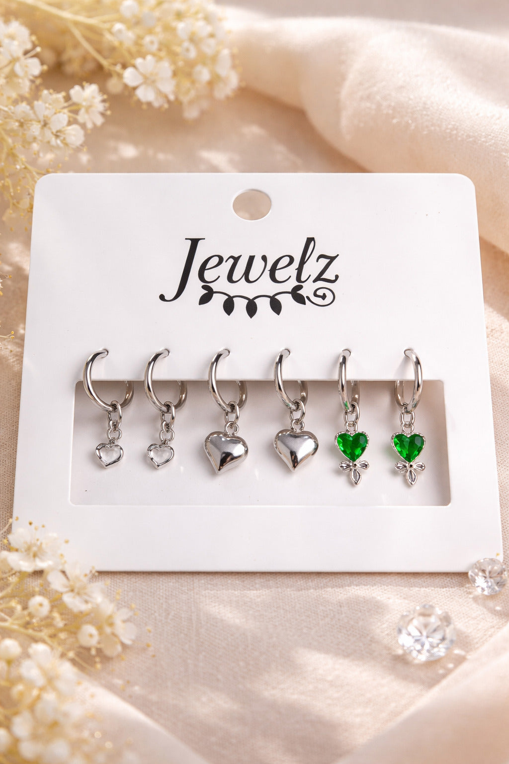 Set of heart-shaped earrings on a 'Jewelz' branded card with decorative flowers.