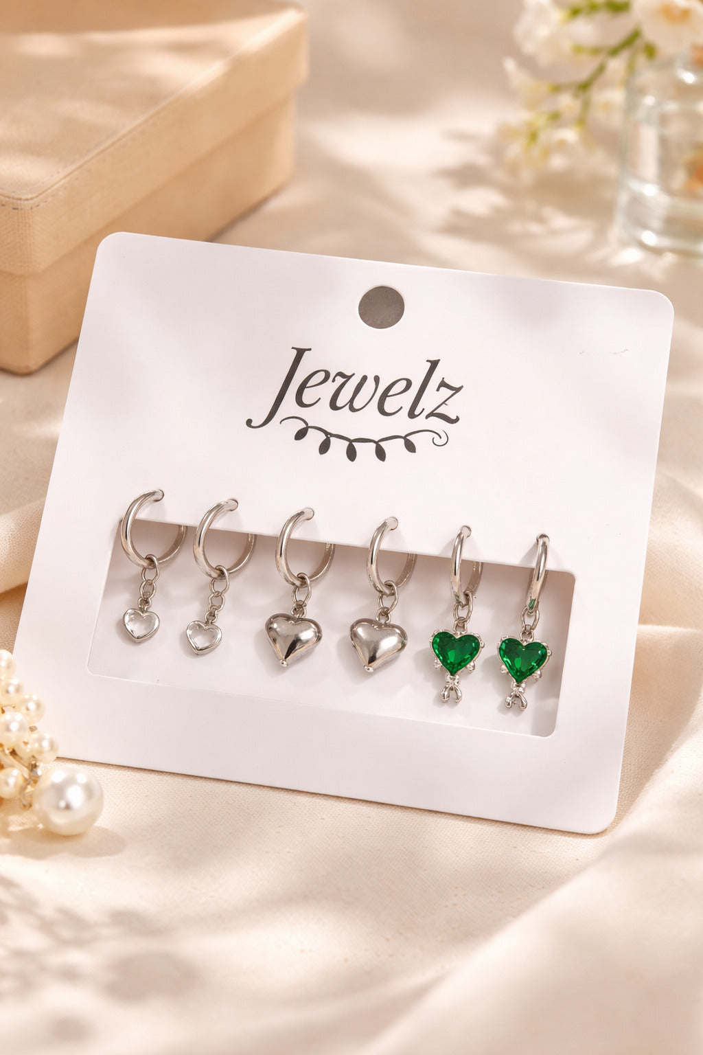 Set of heart-shaped earrings on a 'Jewelz' branded card with a beige background.