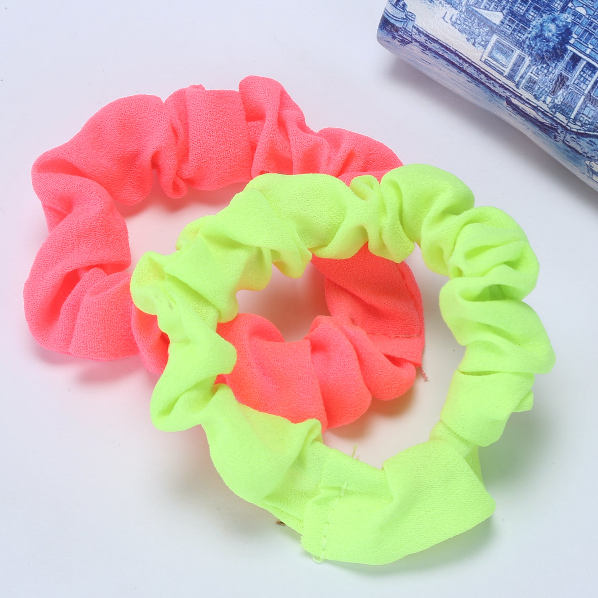 A set of colorful slim rubber bands in pink and green, displayed on a white surface.
