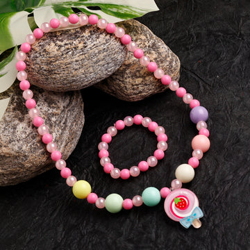 Set of pink and white beaded necklace and bracelet on a dark surface with stones and leaves.