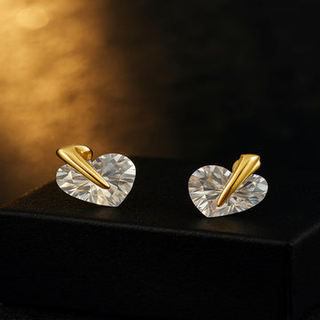 Heart-shaped earrings with gold accents on a dark surface