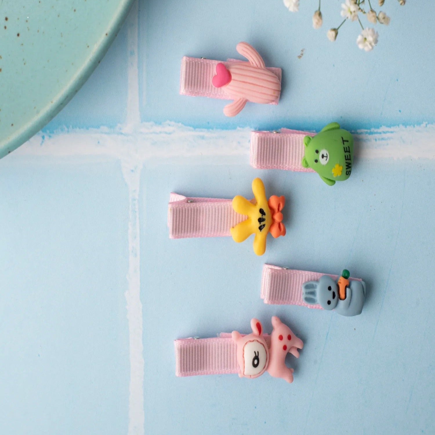 Set of colorful hair clips on a light blue background with flowers.