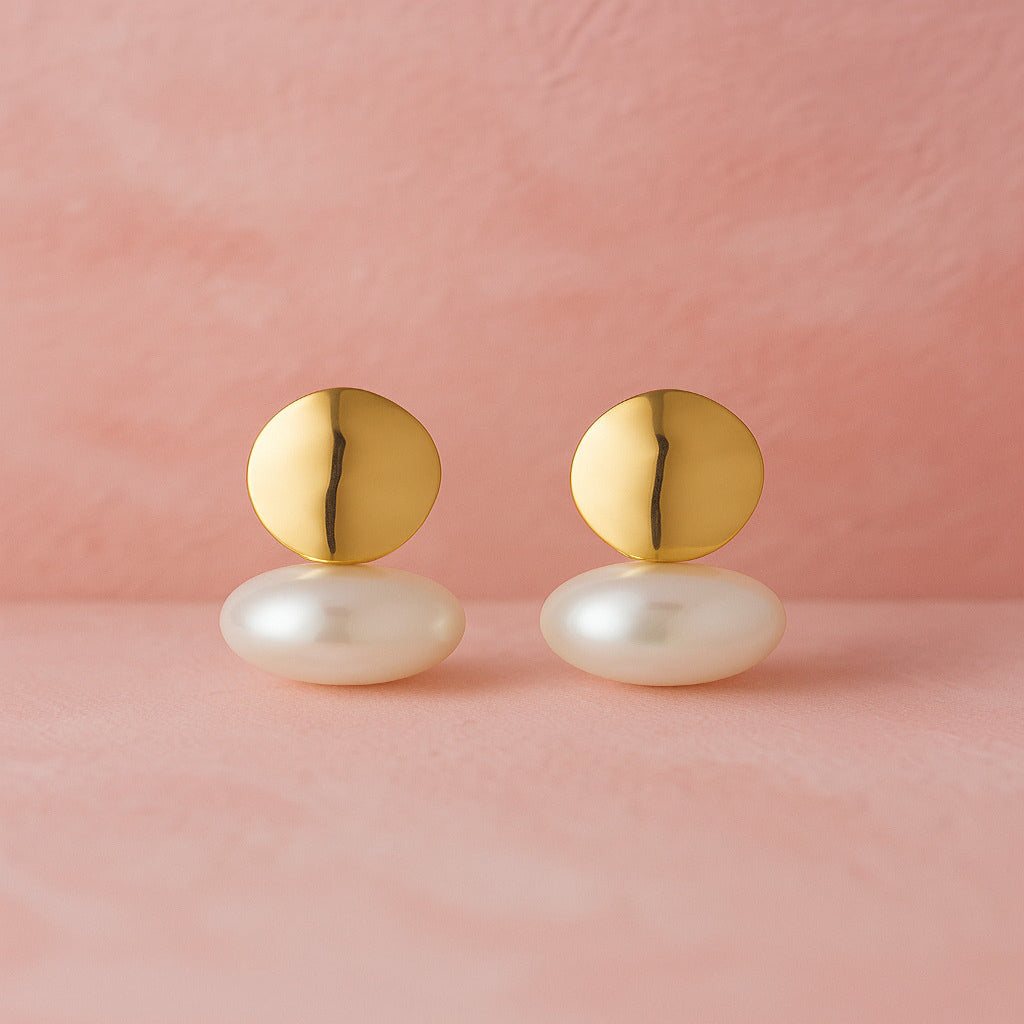 Gold and pearl earrings on a pink background