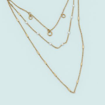 Two gold necklaces on a light blue background