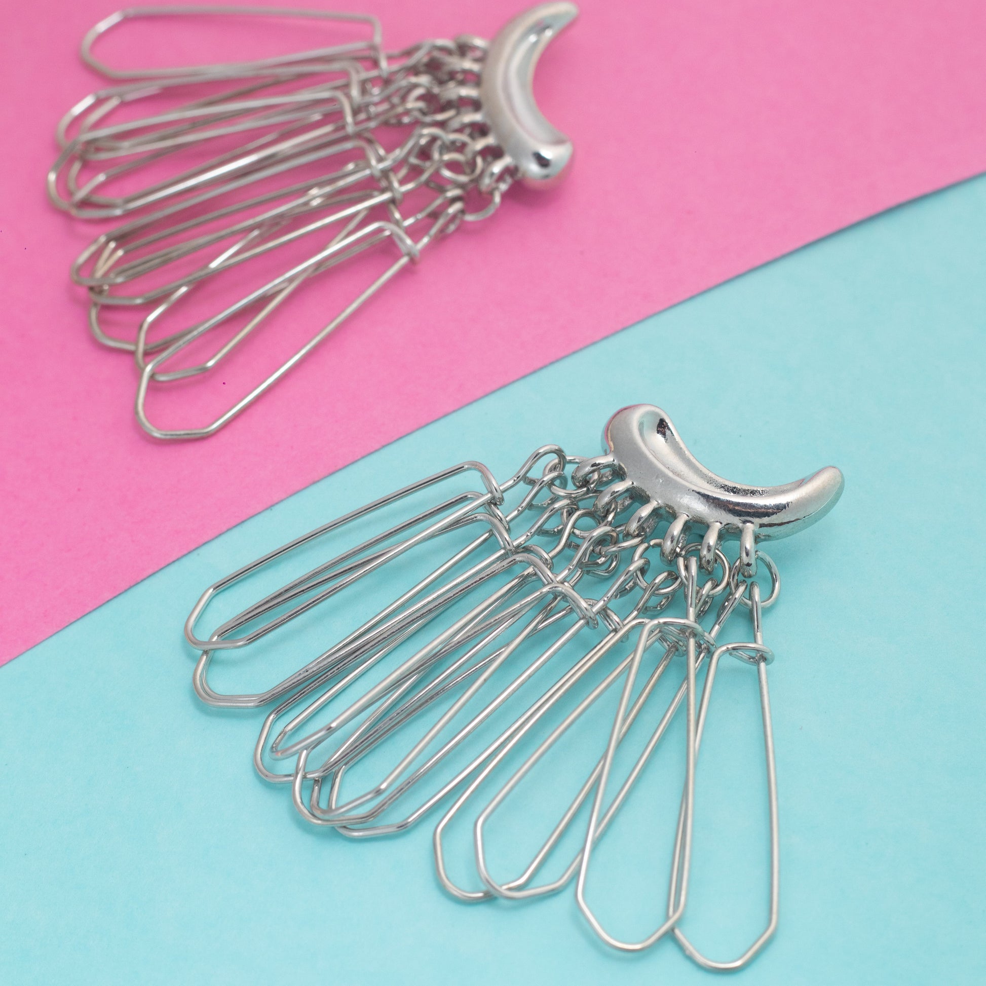 Metal hairpin with crescent moon design on a pink and blue background