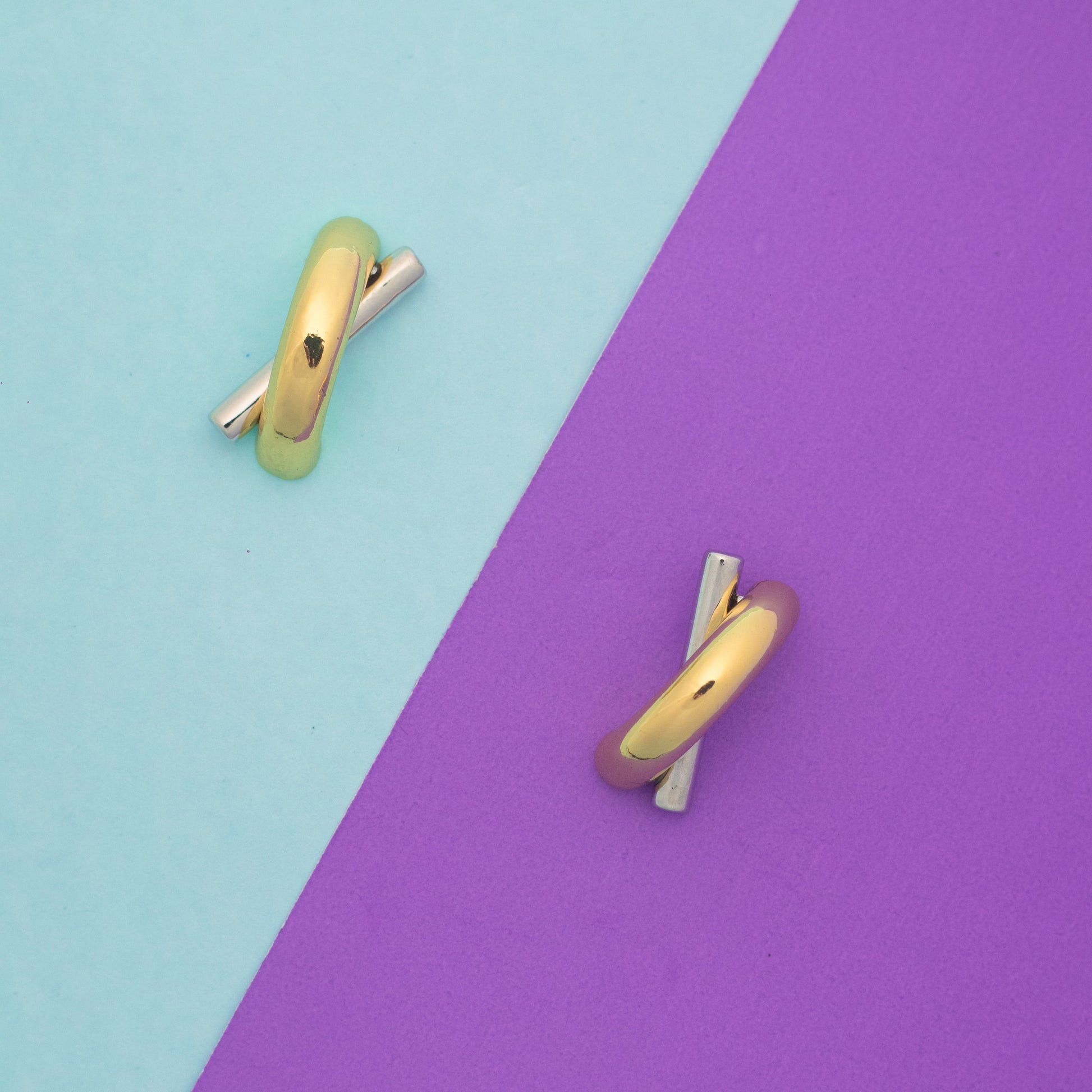 Gold earrings on a two-tone blue and purple background