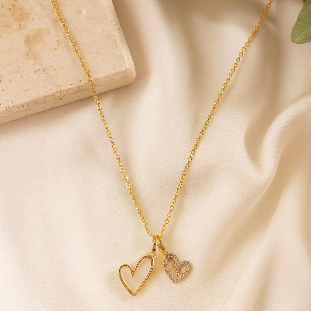 Gold necklace with heart pendants on a beige fabric background