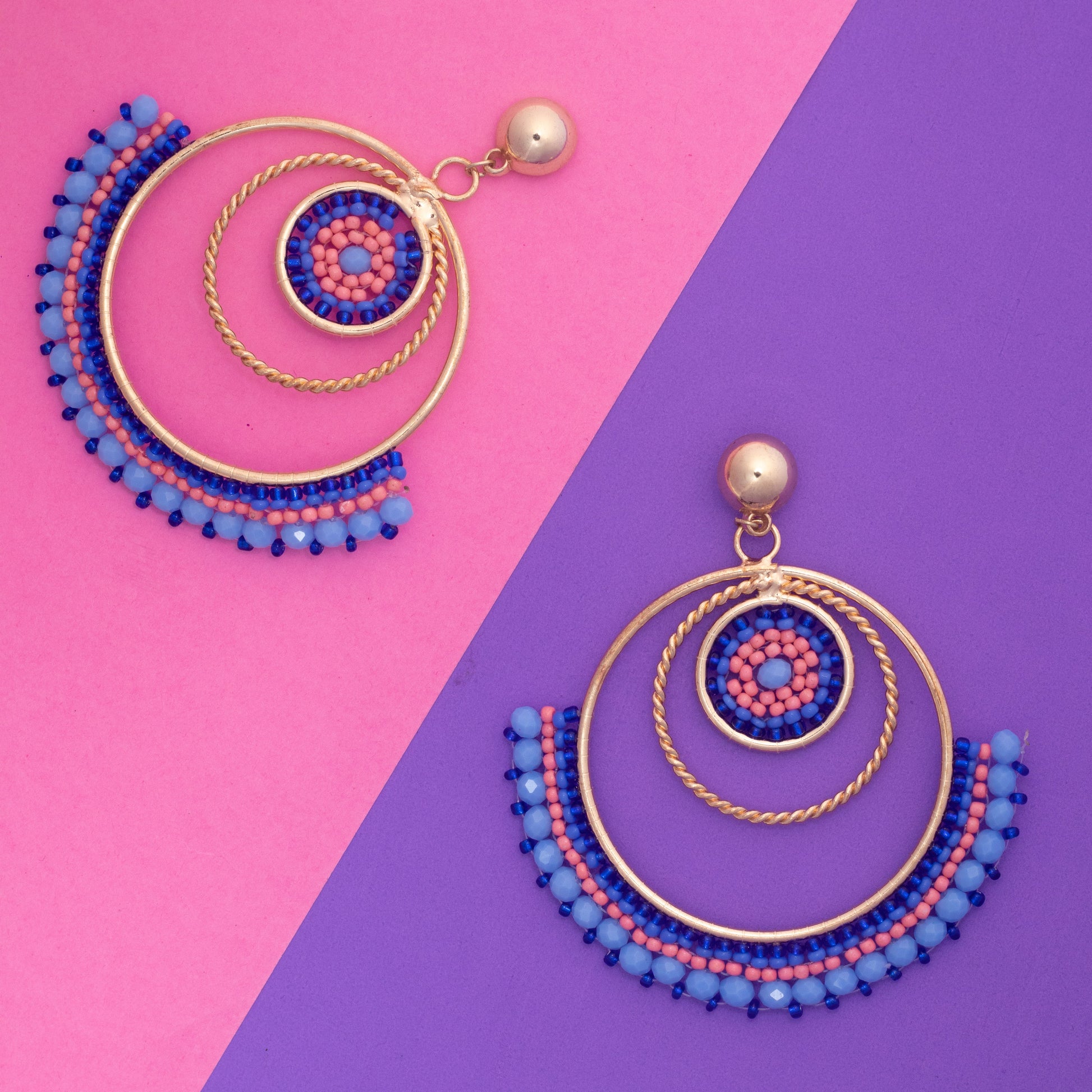 Pair of colorful earrings on a pink and purple background