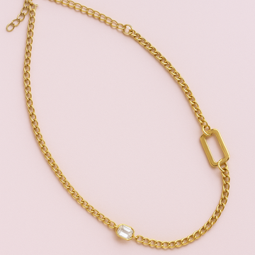 Gold chain necklace with a small pendant on a pink background
