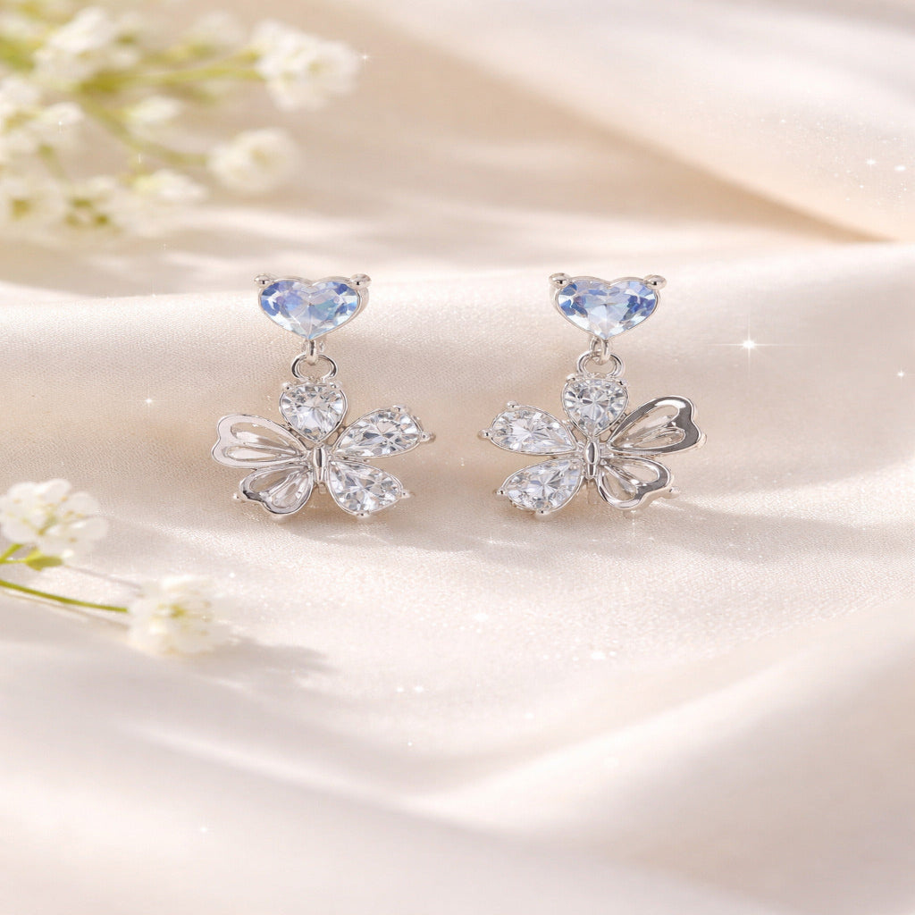 Butterfly-shaped earrings with gemstones on a soft fabric background