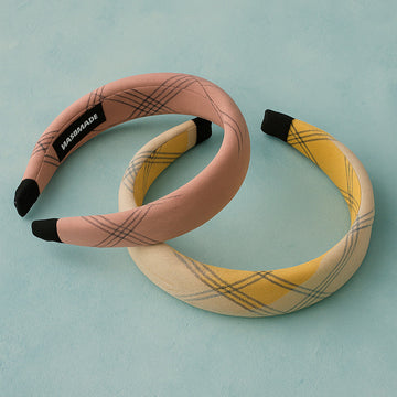 Two plaid headbands, one pink and one yellow, on a light blue background.