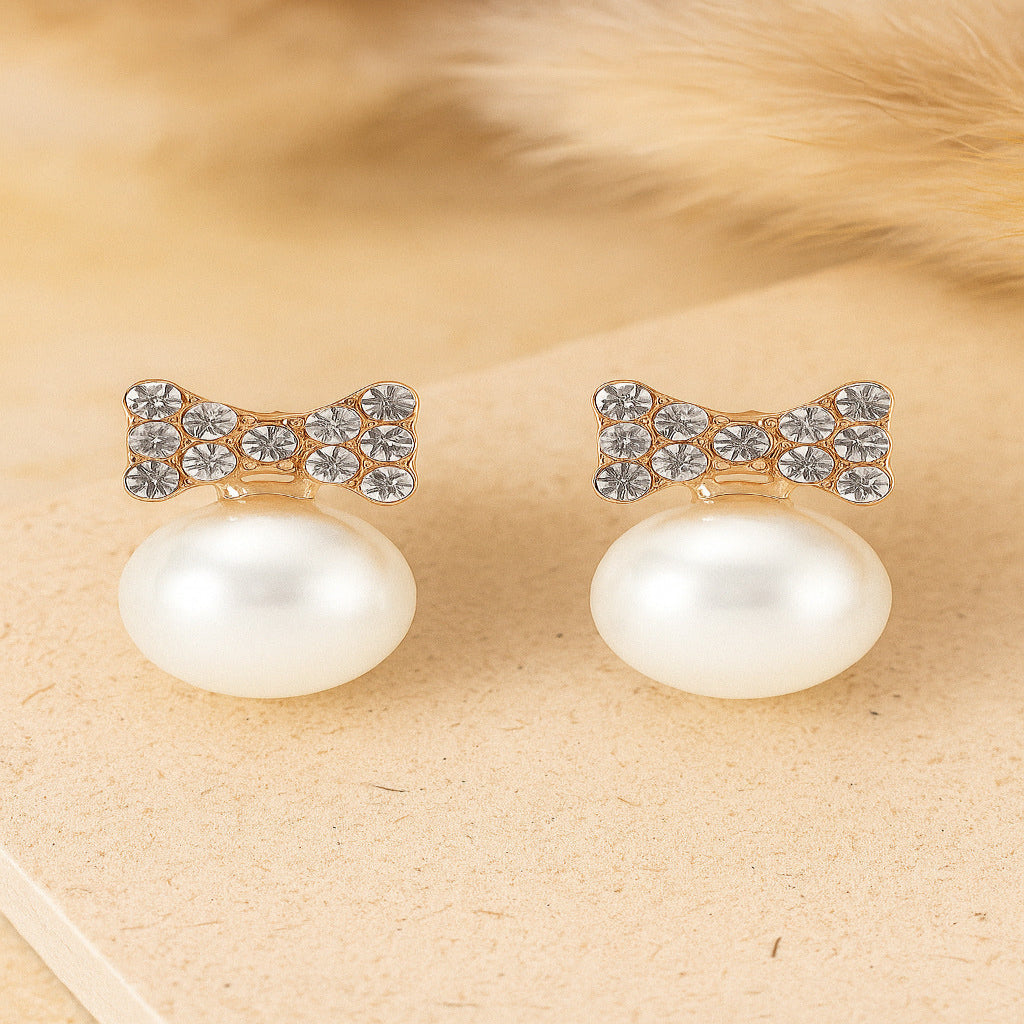 Pearl earrings with bow design on a beige background