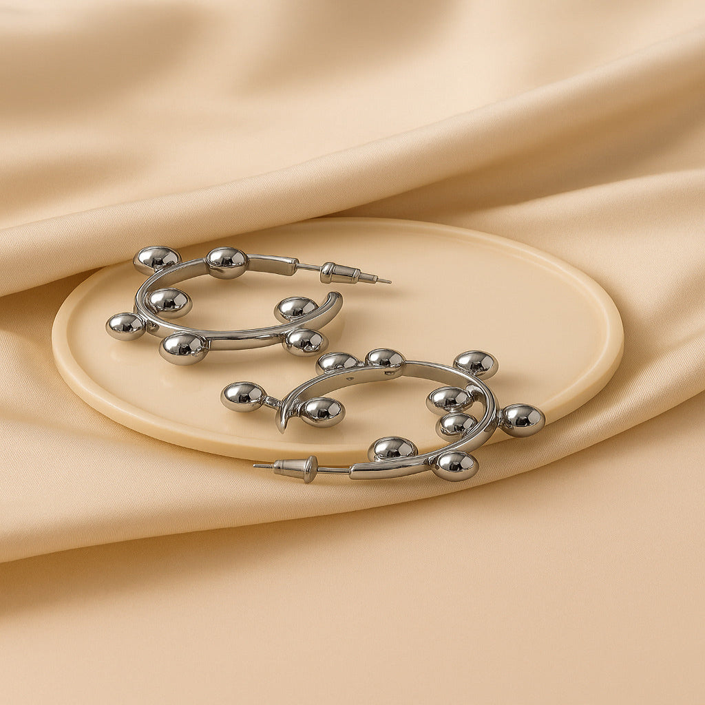 Silver hoop earrings on a beige fabric background