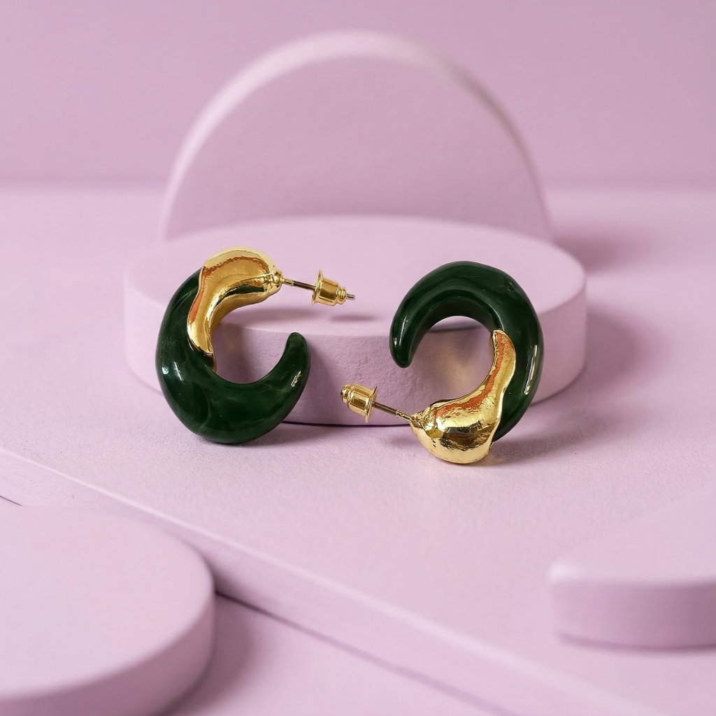 Green and gold hoop earrings on a pink stand