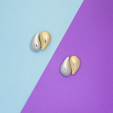 Gold and silver earrings on a two-tone blue and purple background