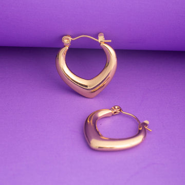 Gold hoop earrings on a purple background