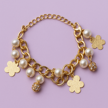Gold bracelet with pearls and flower charms on a purple background