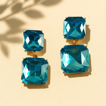 Pair of blue gemstone earrings on a beige background