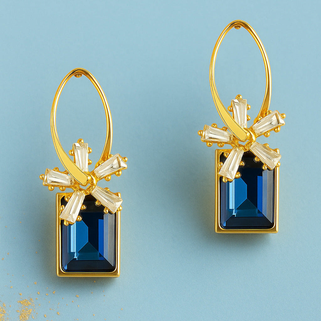 Gold earrings with blue gemstones on a light blue background