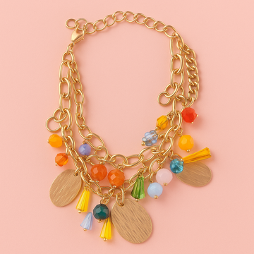 Gold chain necklace with colorful beads and pendants on a pink background