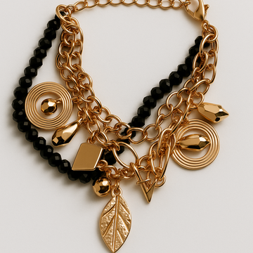 Gold and black beaded bracelet with various charms on a light gray background