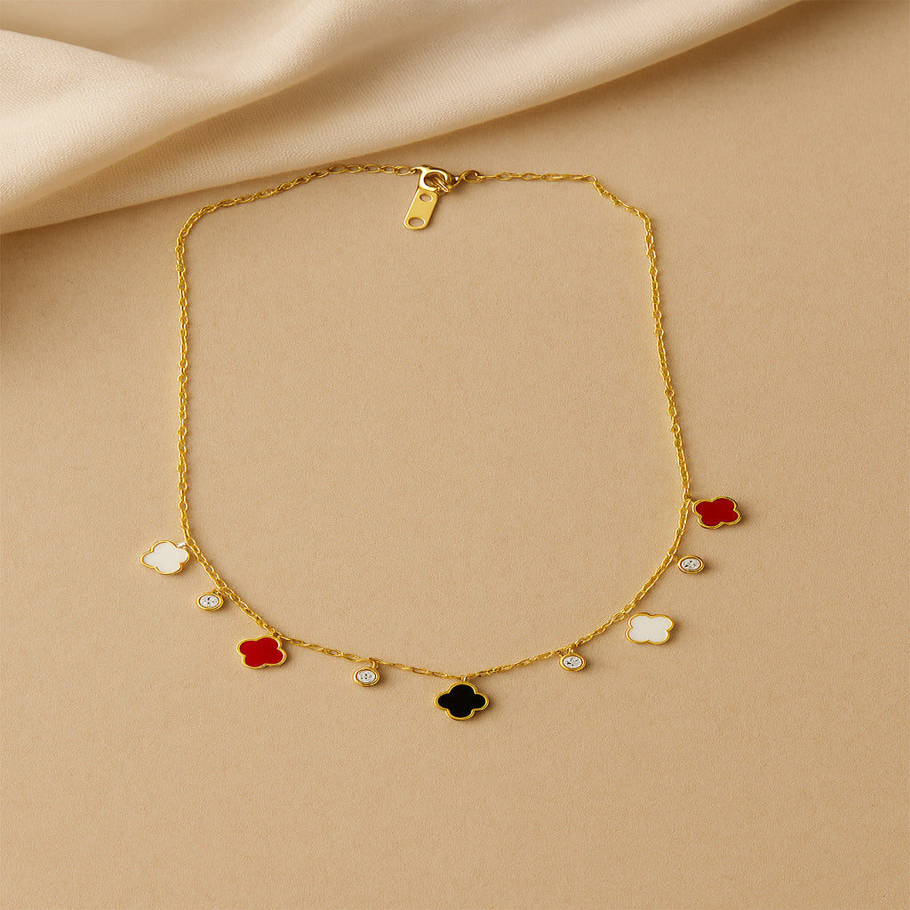 Gold necklace with colorful pendant charms on a beige fabric background