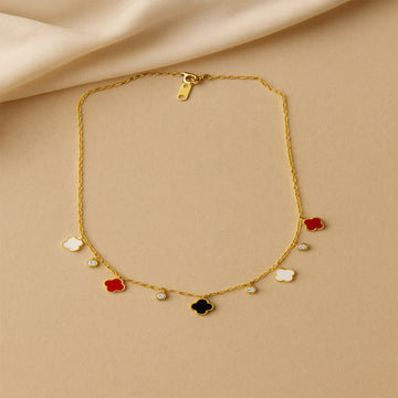 Gold necklace with colorful pendant charms on a beige fabric background