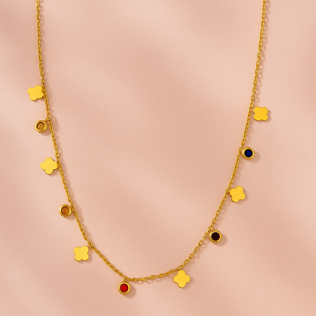 Gold necklace with colorful pendants on a pink background
